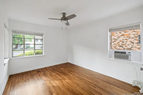 a view of empty room with wooden floor and fan