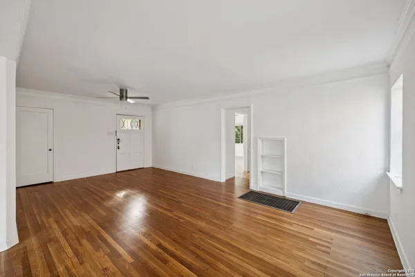 an empty room with wooden floor and windows