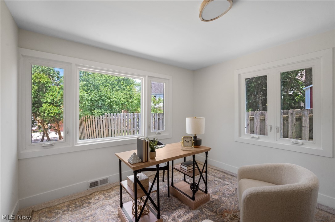 22625 Rye Road Shaker Heights, OH 44122 - Photo 15 of 38 Bright interior space featuring white walls and trim, wood-finish flooring with an area rug, and multiple windows overlooking a wooden fence and greenery
