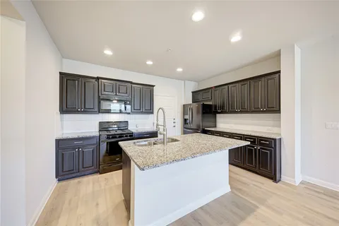 a kitchen with stainless steel appliances granite countertop a stove top oven a sink dishwasher and wooden cabinets with wooden floor