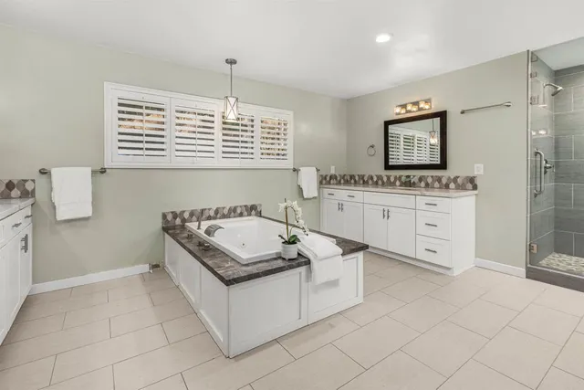 a bathroom with a granite countertop sink mirror and a bathtub
