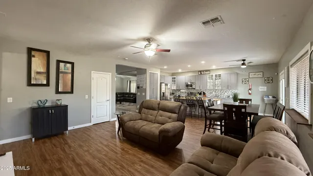 a living room with furniture kitchen view and a wooden floor