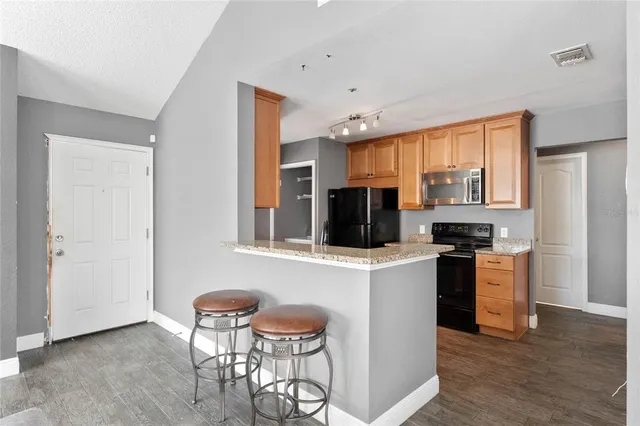 a kitchen with stainless steel appliances granite countertop a stove top oven a sink a dining table and chairs with wooden floor