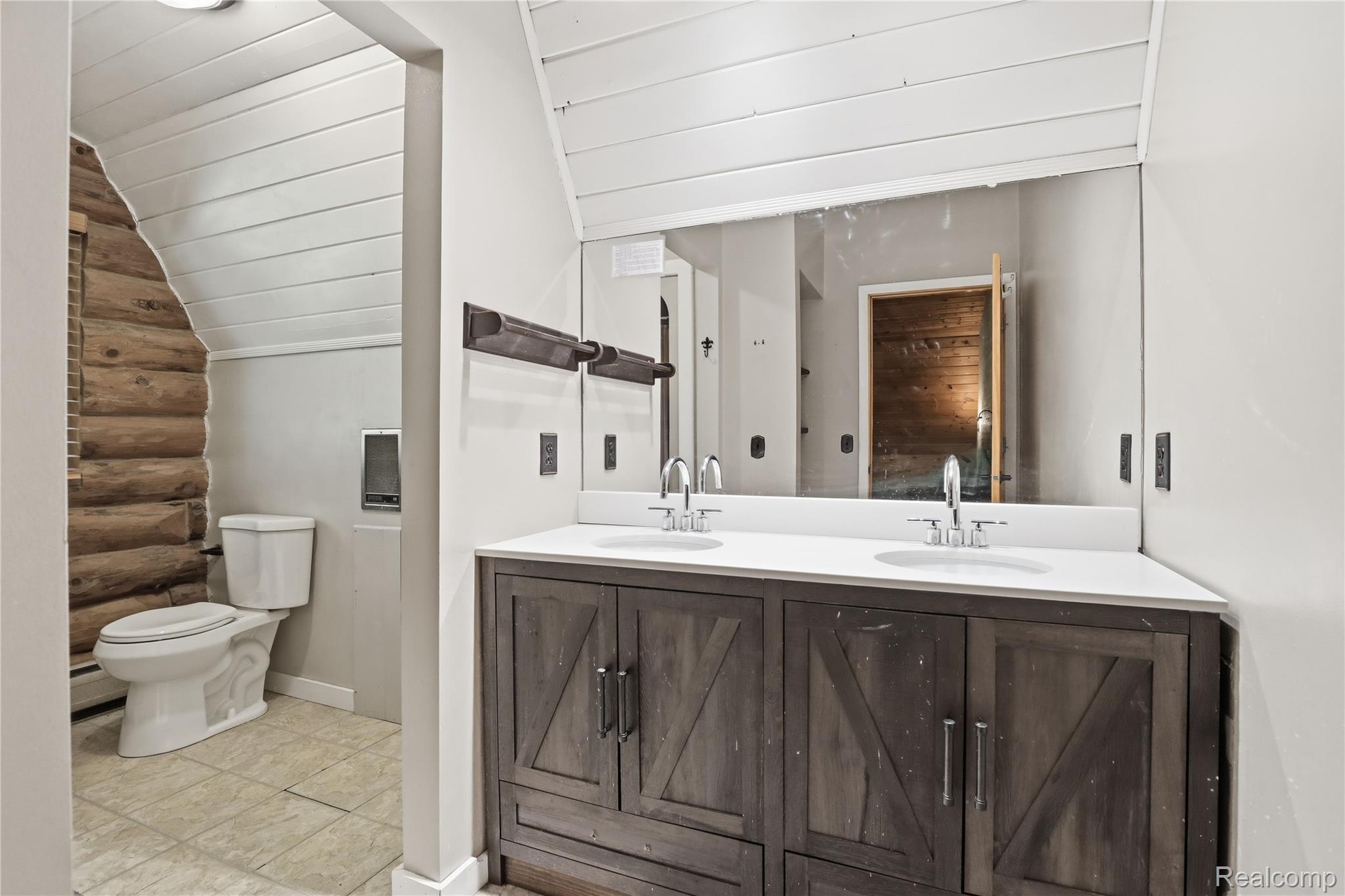 14830 Sheridan Road Byron, MI 48418 - Photo 29 of 74 Double vanity with a white countertop and integrated sinks, barn door style cabinetry with dark hardware, and a large wall-mounted mirror