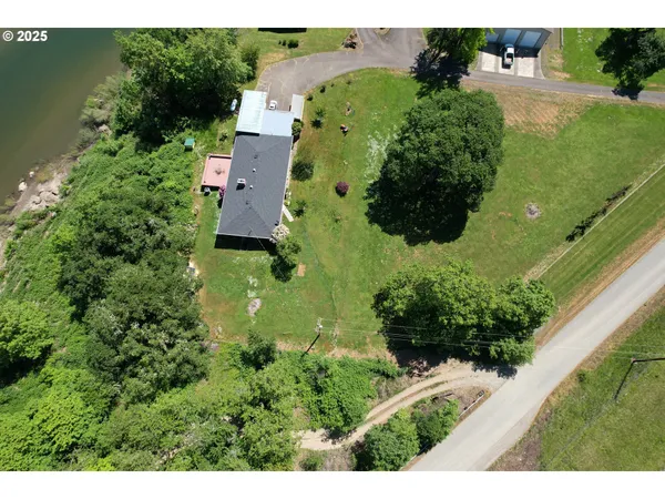 an aerial view of residential house with outdoor space and trees all around