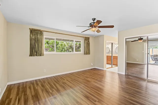 a view of an empty room with window and wooden floor