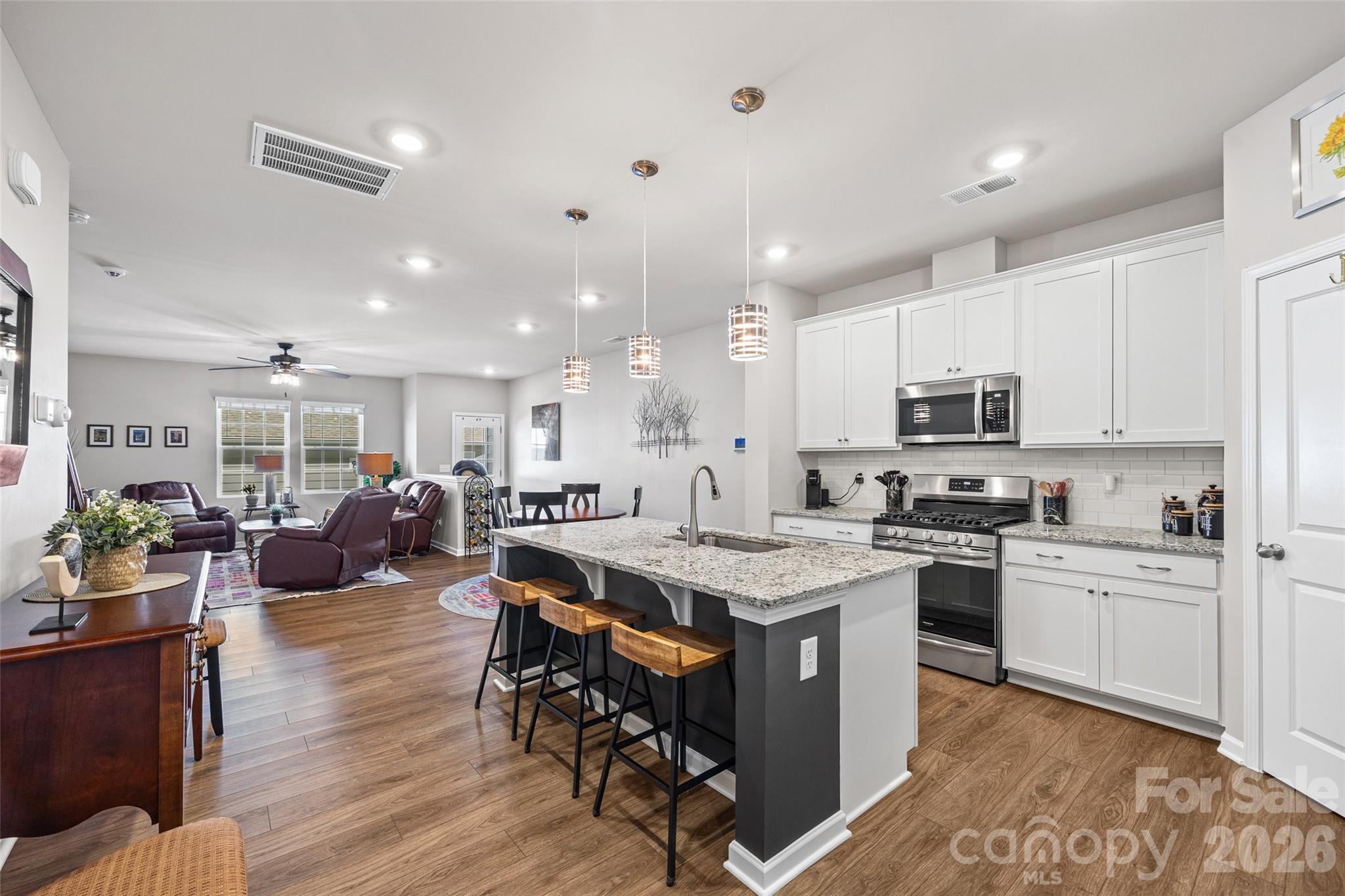 909 Cobbled Way Fort Mill, SC 29715 - Photo 5 of 31 a kitchen with stainless steel appliances kitchen island granite countertop a table chairs sink and cabinets