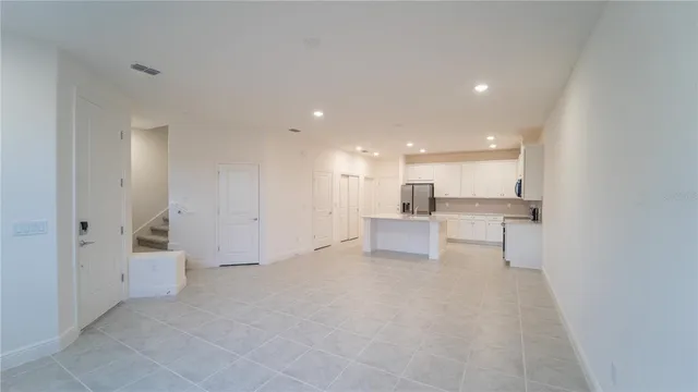a view of an empty room and a kitchen