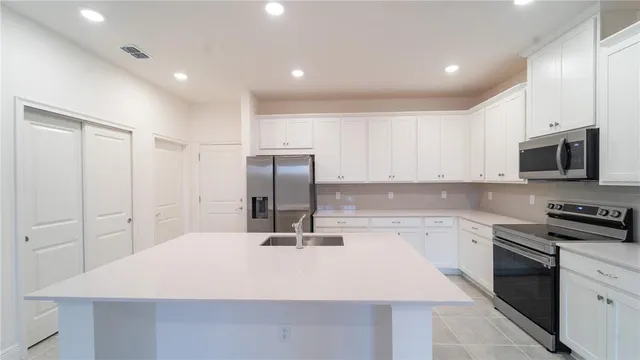 a kitchen with kitchen island a sink appliances and cabinets