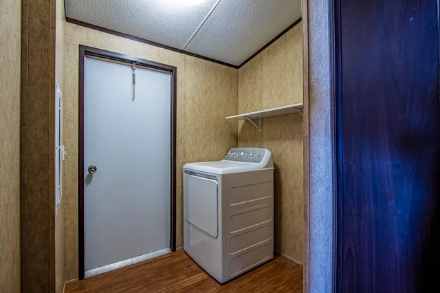a view of a hallway with wooden floor and a bathroom