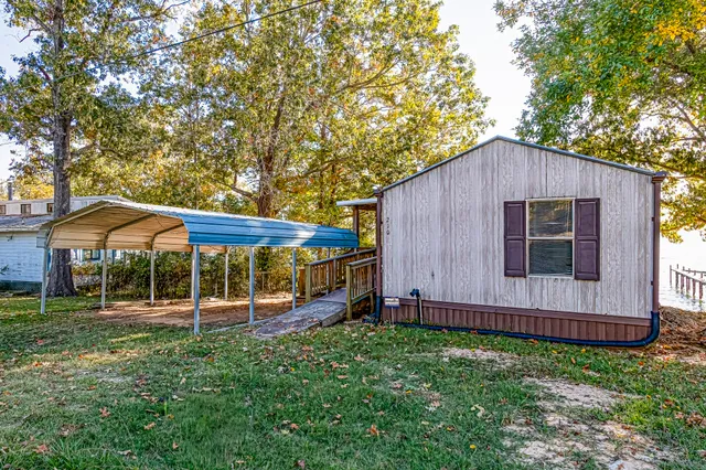 a backyard of a house with wooden fence and a large tree
