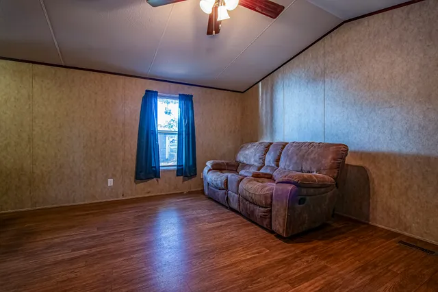a living room with stainless steel appliances kitchen island granite countertop wooden floors and a large window