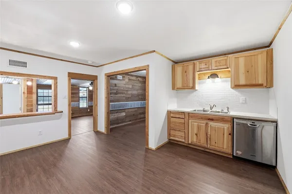a kitchen with stainless steel appliances granite countertop a sink cabinets and wooden floor