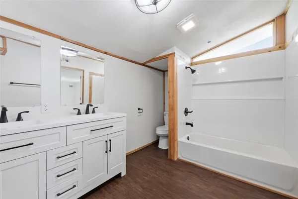 a en suite bathroom with a granite countertop sink a toilet a mirror and shower