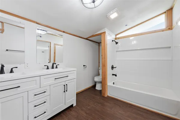 a bathroom with a double vanity sink a toilet a mirror and shower