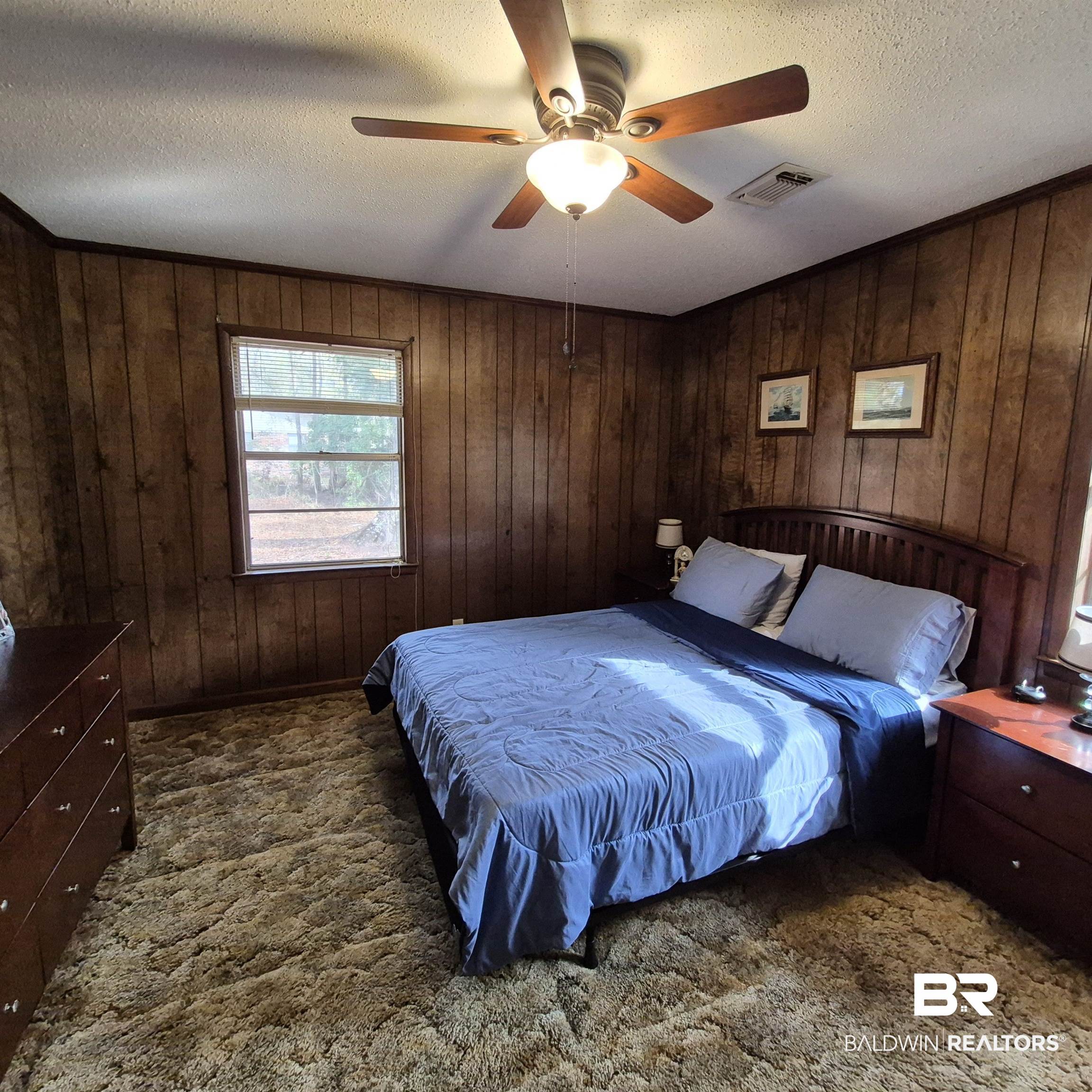 491 Forrest Avenue Castleberry, AL 36432 - Photo 14 of 33 Bedroom with wooden walls, a textured ceiling, ceiling fan, and dark colored carpet