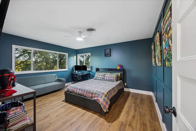 a bedroom with a bed and a large window with wooden floor