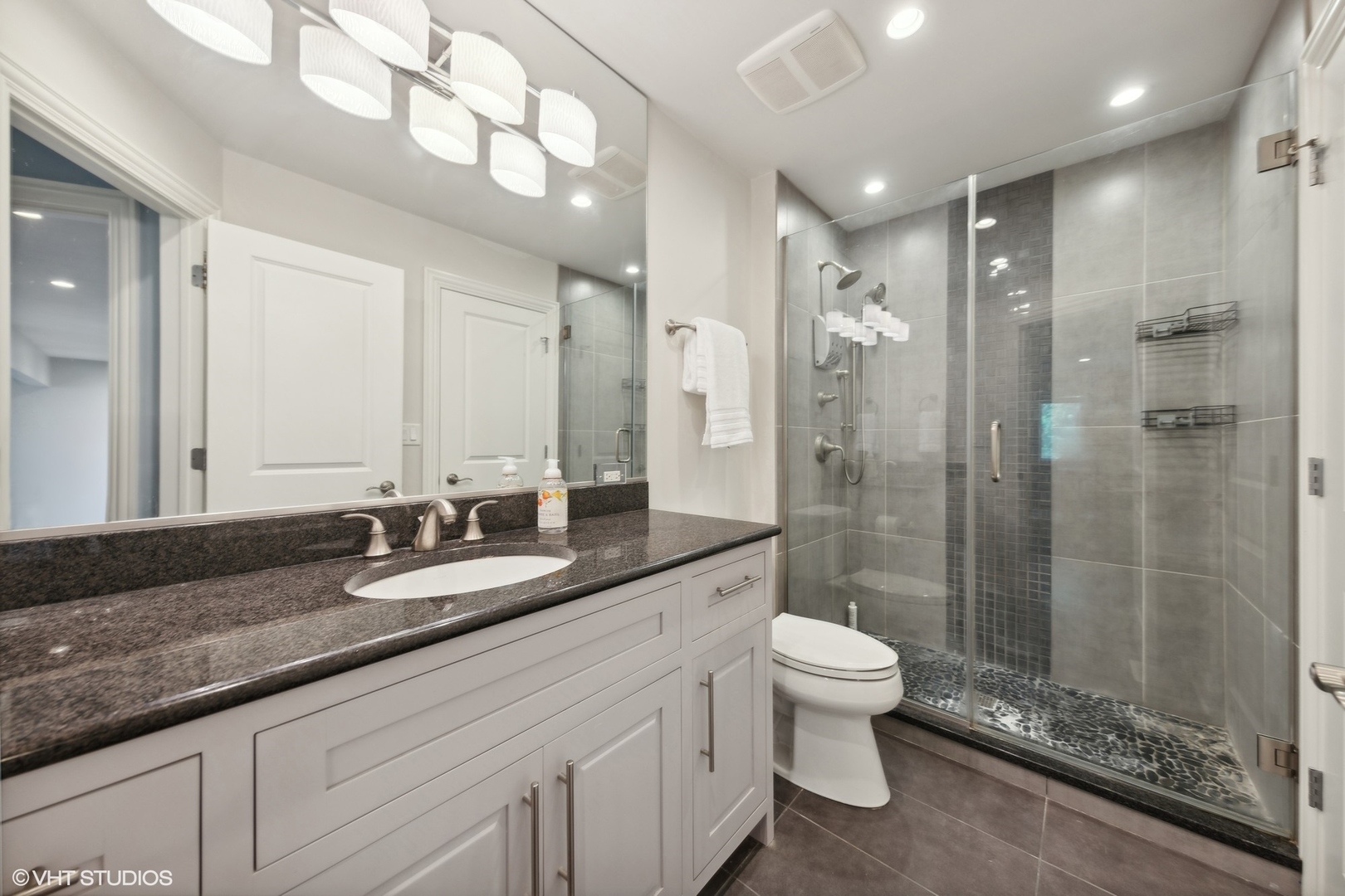6 Bel Aire Court Burr Ridge, IL 60527 - Photo 20 of 37 a bathroom with a granite countertop sink a toilet a mirror and a glass door shower