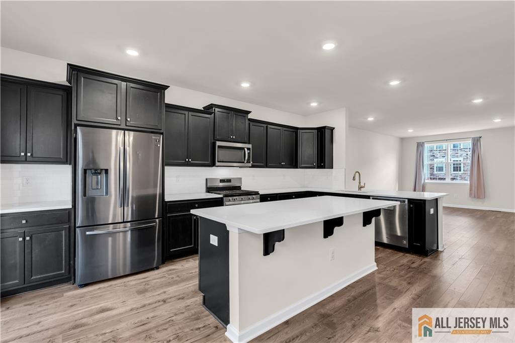 504 East International Road, Unit 504 Monroe Township, NJ 08831 - Photo 11 of 29 a kitchen with kitchen island a sink stainless steel appliances and cabinets
