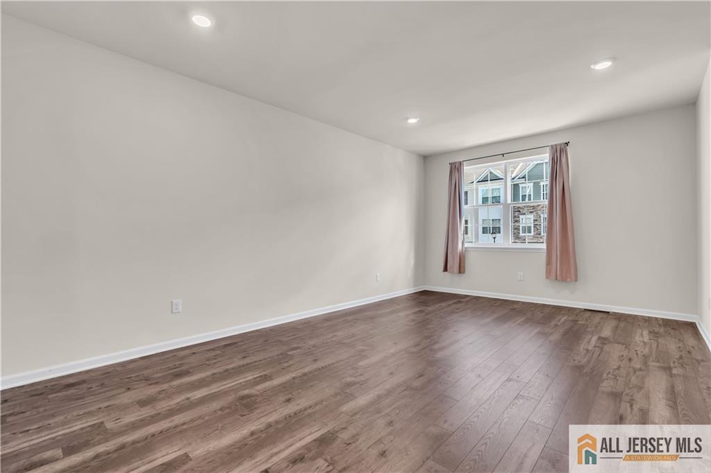 504 East International Road, Unit 504 Monroe Township, NJ 08831 - Photo 5 of 29 a view of an empty room with wooden floor and a window
