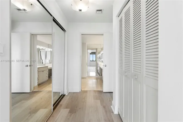 a view of a hallway with wooden floor and a bathroom