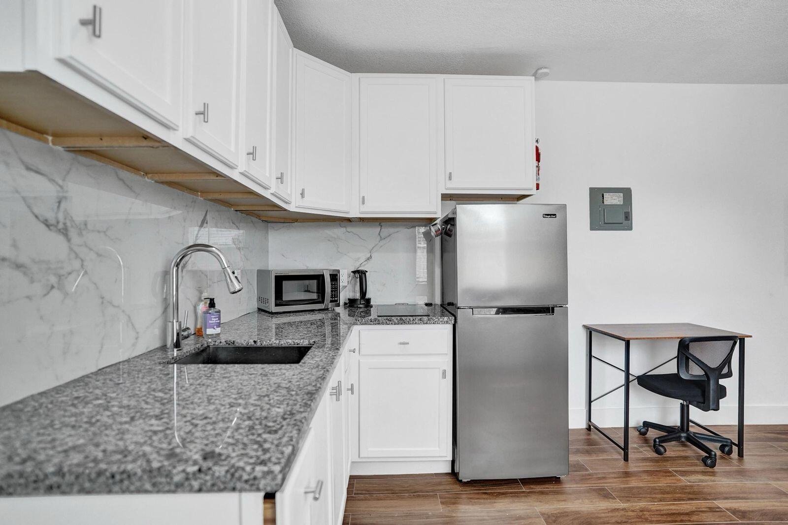 1075 West 30th Street Riviera Beach, FL 33404 - Photo 26 of 66 a kitchen with stainless steel appliances granite countertop a refrigerator a stove and a sink with granite countertops