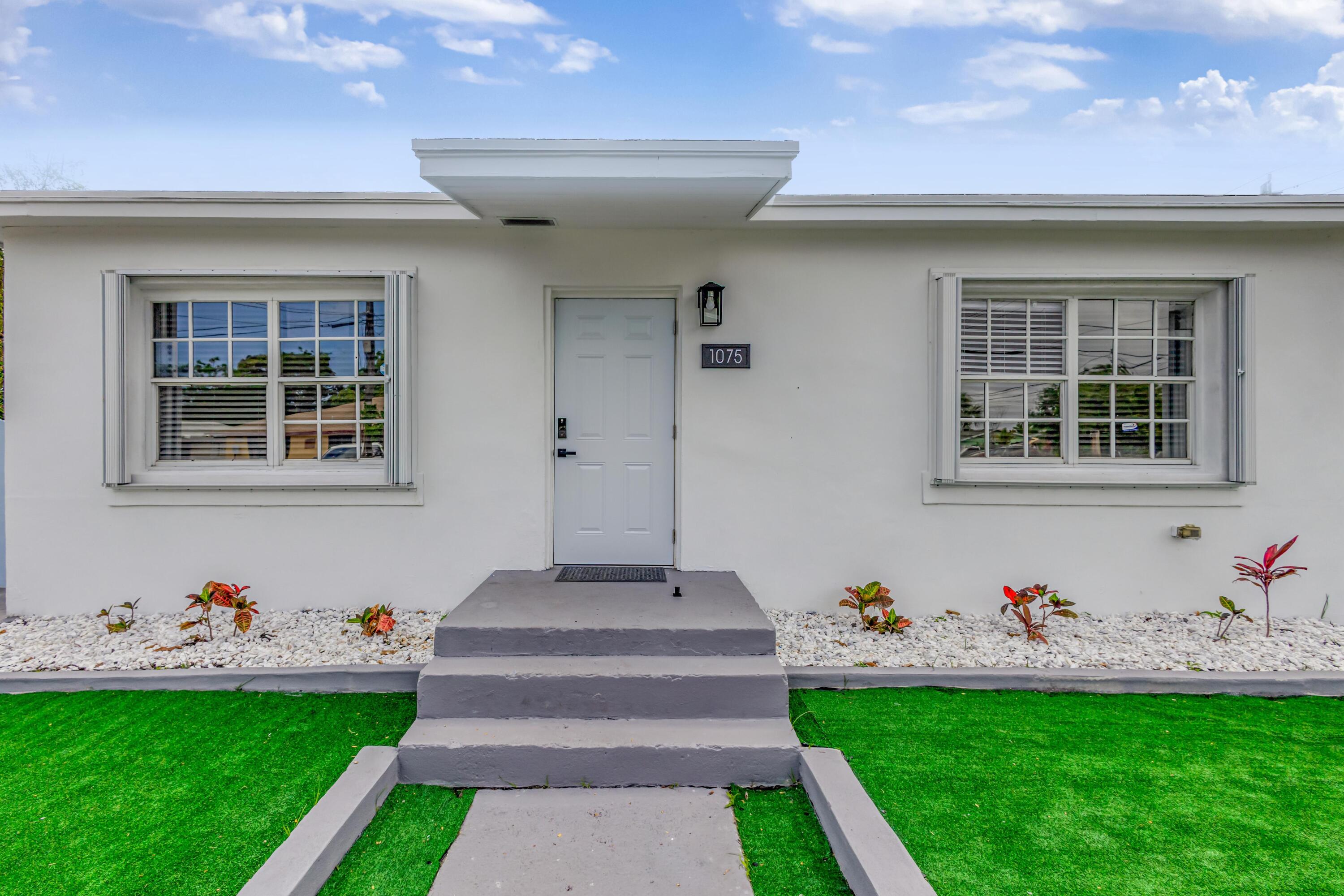 1075 West 30th Street Riviera Beach, FL 33404 - Photo 3 of 66 a front view of a house with garden