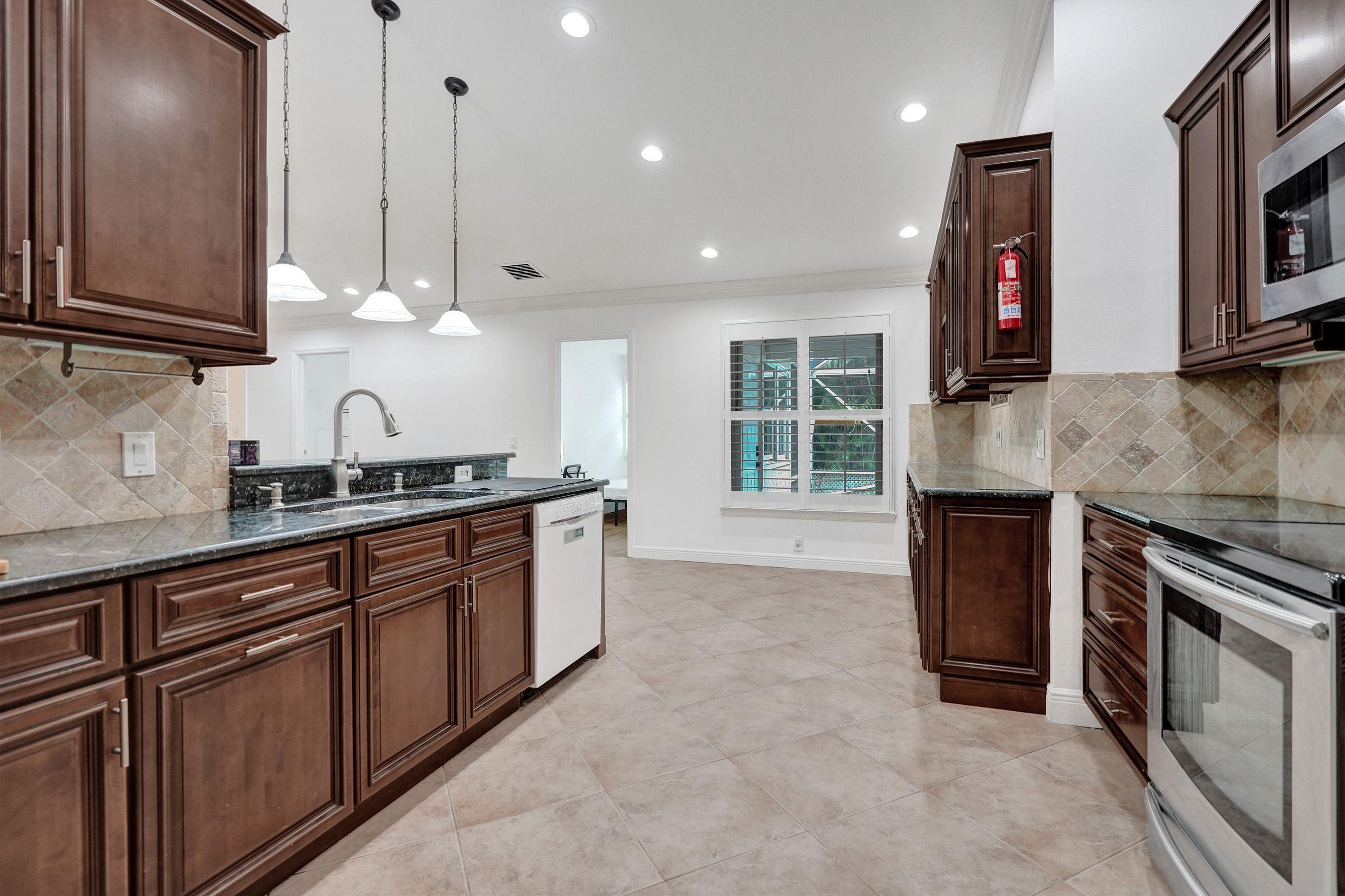 1075 West 30th Street Riviera Beach, FL 33404 - Photo 35 of 66 a kitchen with stainless steel appliances granite countertop a stove a sink and a microwave