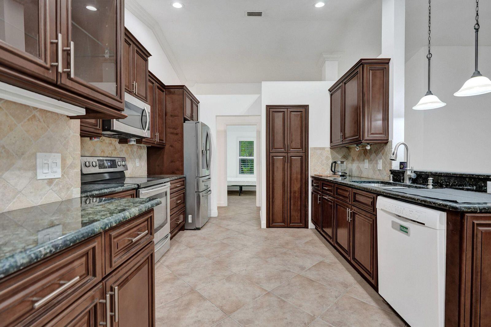 1075 West 30th Street Riviera Beach, FL 33404 - Photo 36 of 66 a kitchen with stainless steel appliances granite countertop a sink stove and refrigerator