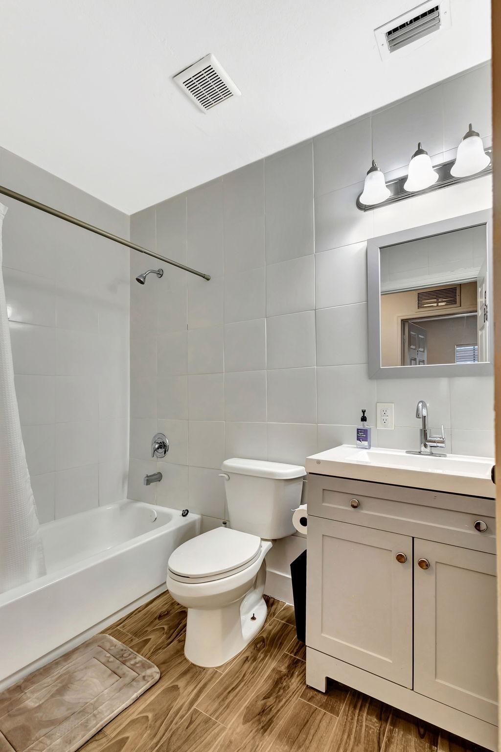 1075 West 30th Street Riviera Beach, FL 33404 - Photo 9 of 66 a bathroom with a toilet a sink a mirror a bathtub and vanity