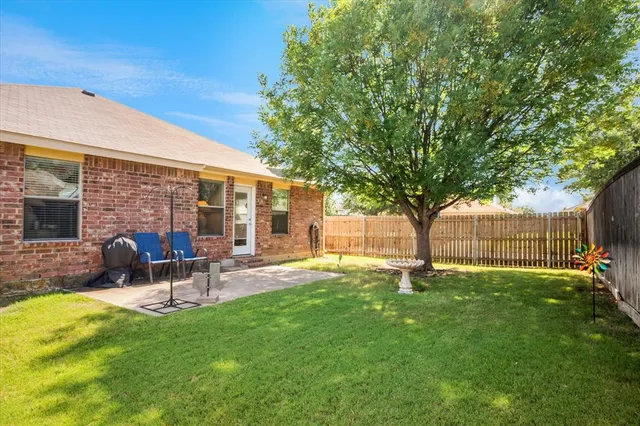 a view of a backyard with table and chairs and a large tree