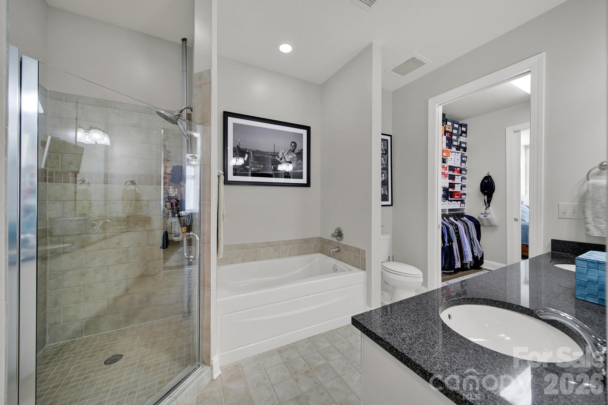 230 South Tryon Street, Unit 1004 Charlotte, NC 28281 - Photo 14 of 39 a bathroom with a granite countertop sink a mirror a bathtub and shower