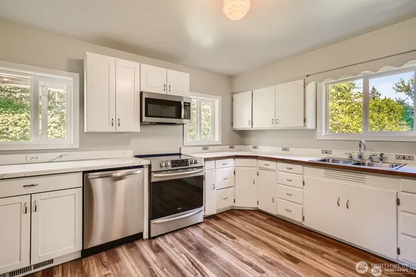 a kitchen with granite countertop white cabinets a sink and a oven with wooden floor