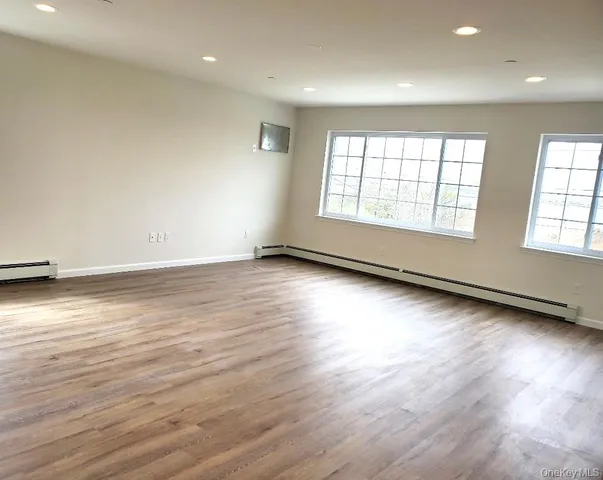 an empty room with wooden floor and windows with curtains