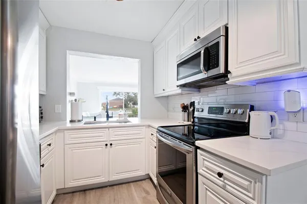 a kitchen with white cabinets and sink