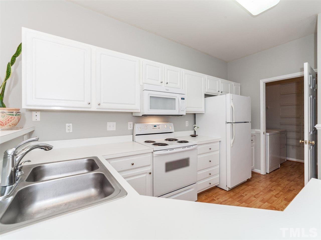 7030 Sandy Forks Road, Unit 102 Raleigh, NC 27615 - Photo 6 of 25 a kitchen with white cabinets and white appliances