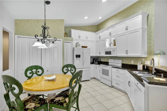 a kitchen with stainless steel appliances granite countertop a sink a stove a refrigerator a dining table and chairs