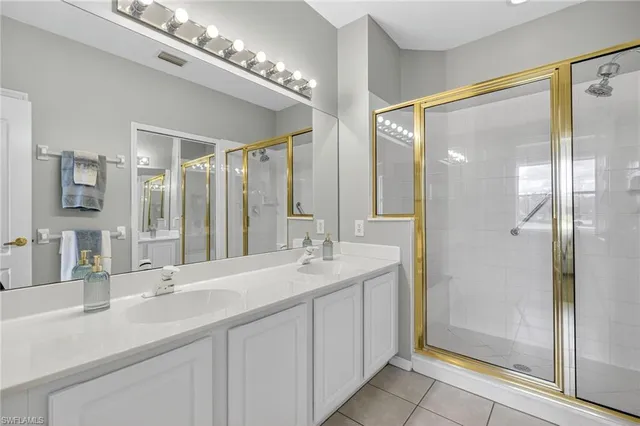 a bathroom with a double vanity sink mirror and shower