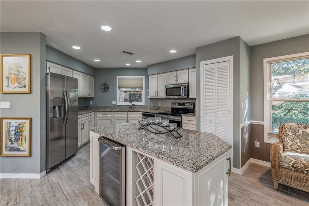 6652 Trident Way, Unit J1 Naples, FL 34108 - Photo 6 of 20 a kitchen with stainless steel appliances granite countertop a refrigerator a stove a sink a dining table and chairs with wooden floor