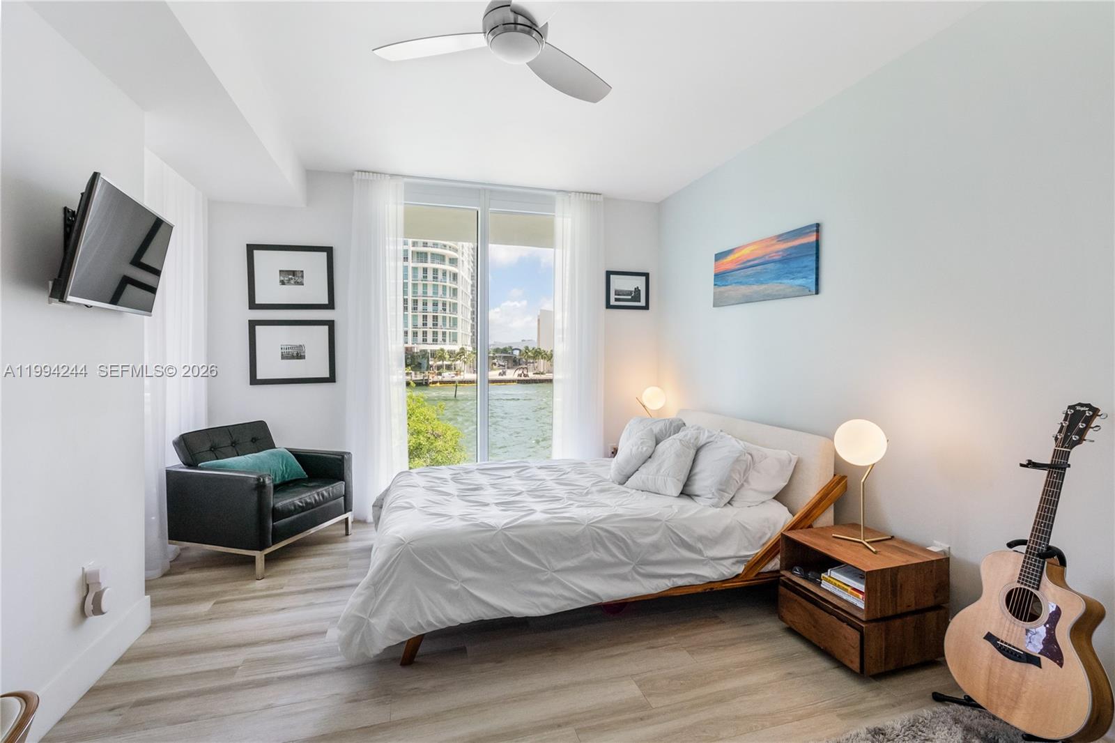 901 Brickell Key Boulevard, Unit 305 Miami, FL 33131 - Photo 12 of 31 a bedroom with a bed wooden floor and flat screen tv