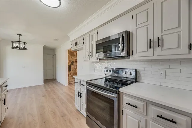 a kitchen with stainless steel appliances granite countertop a stove a microwave and a hard wood floors