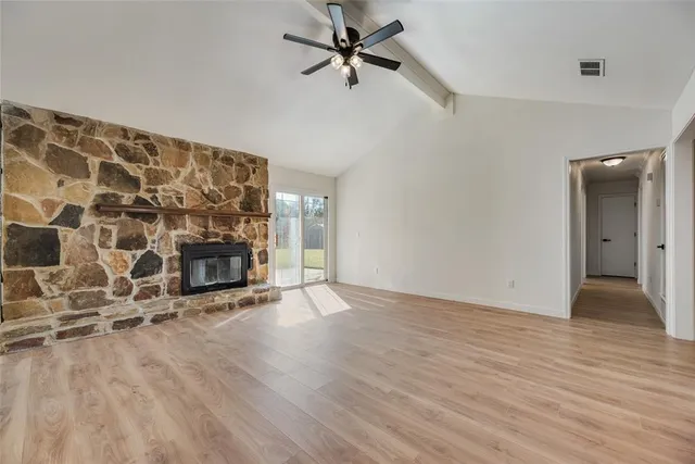an empty room with wooden floor a fireplace and windows