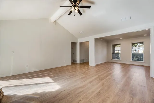 a view of an empty room with window and wooden floor