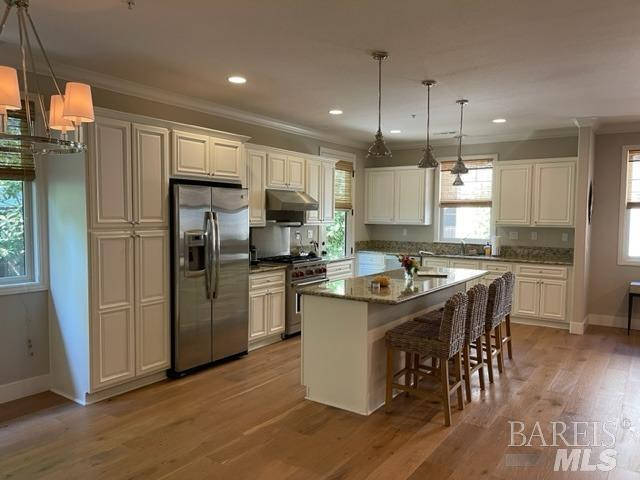a kitchen with stainless steel appliances granite countertop a sink a stove a refrigerator and island with wooden floor