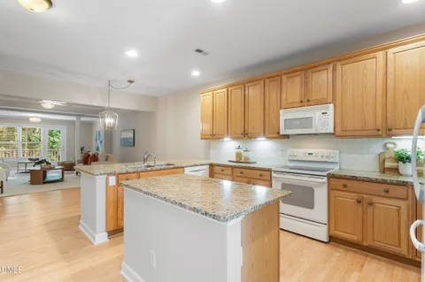 a kitchen with granite countertop a sink and dishwasher with white cabinets