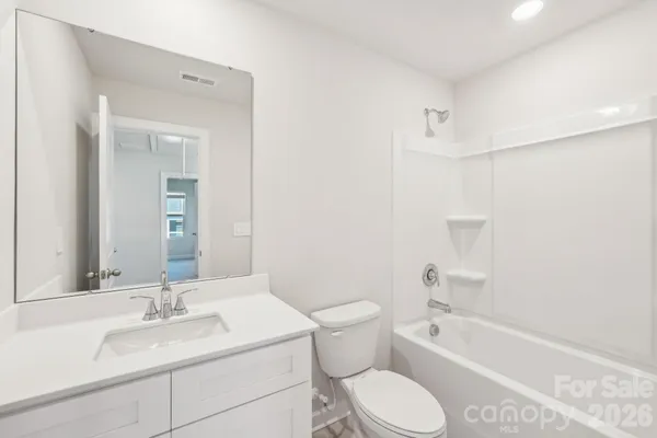 a bathroom with a granite countertop sink toilet mirror and bathtub