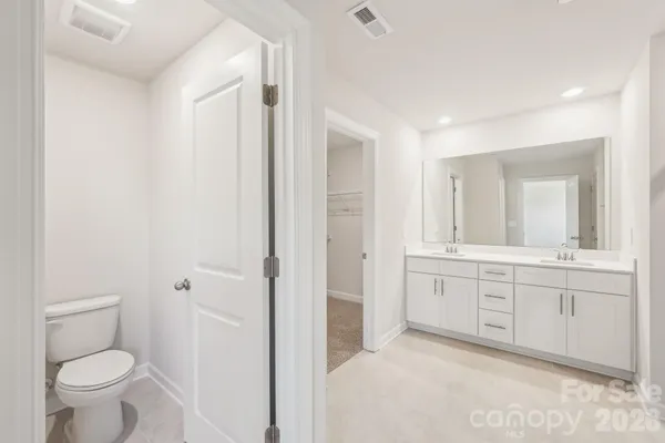 a spacious bathroom with a granite countertop sink a toilet and a mirror