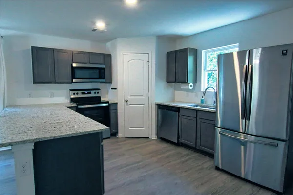 a kitchen with stainless steel appliances granite countertop a refrigerator and a stove top oven