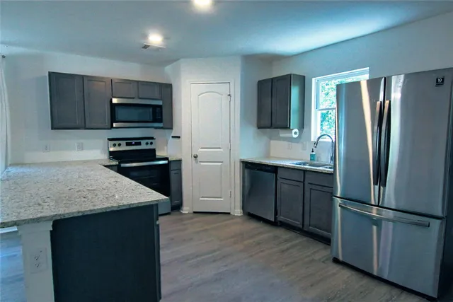 a kitchen with stainless steel appliances granite countertop a refrigerator and a stove top oven