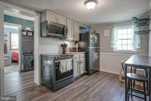 a kitchen with stainless steel appliances a stove a refrigerator cabinets and a wooden floor